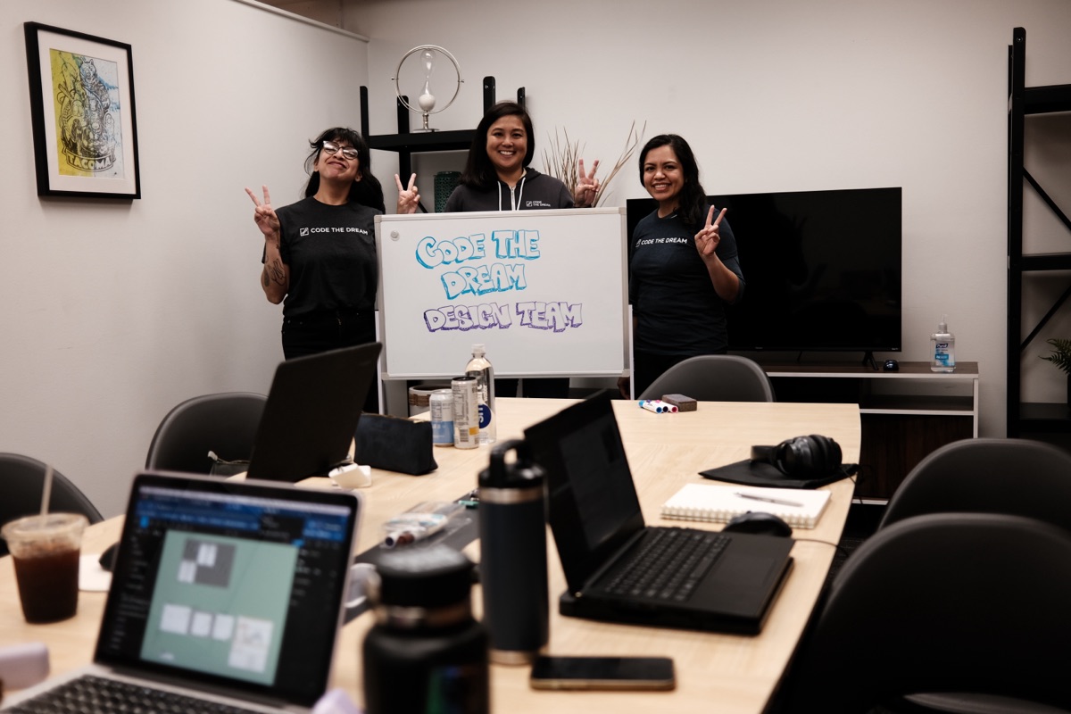 Three members of the Code the Dream design team beside a whiteboard.